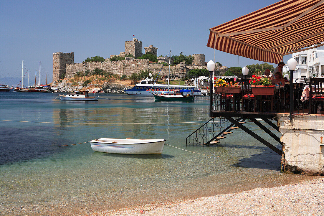 Beach restaurant and view to Castle of St Peter, Bodrum, Aegean, Turkey