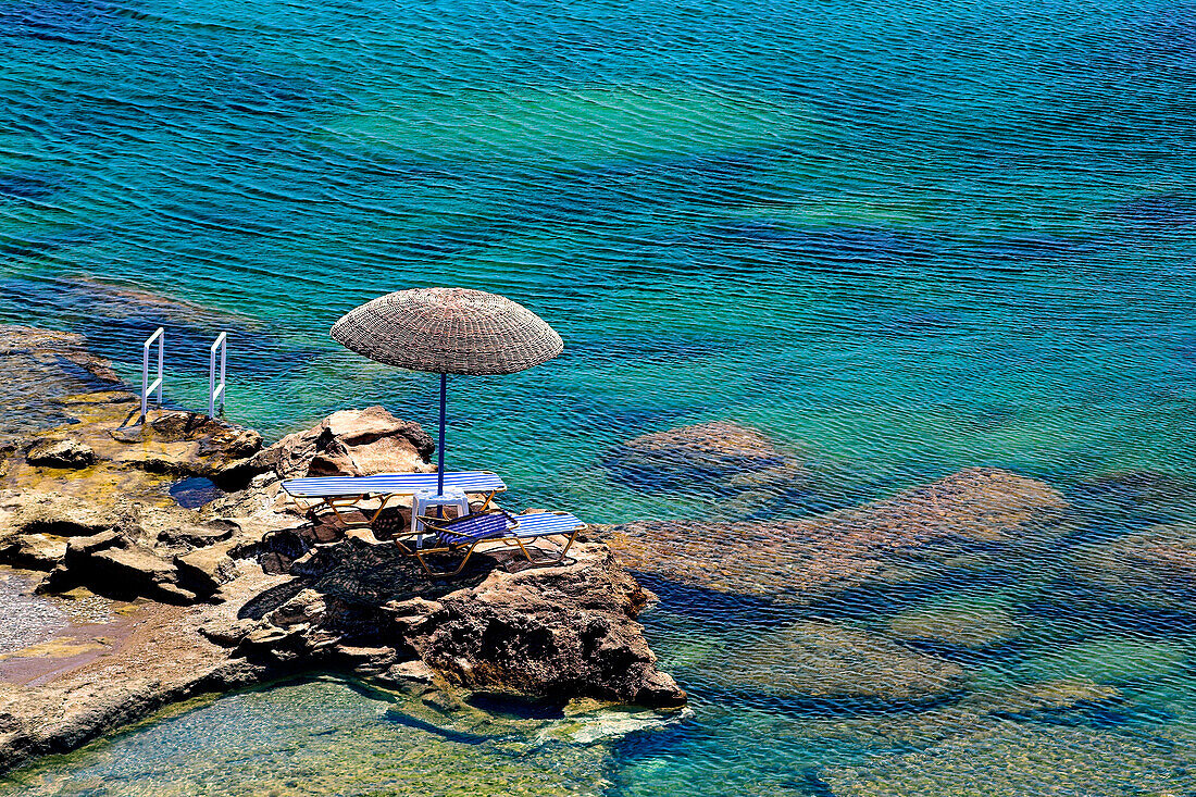 Parasol and loungers at the water's edge, Kalithea Bay, Rhodes Island, Greek Islands