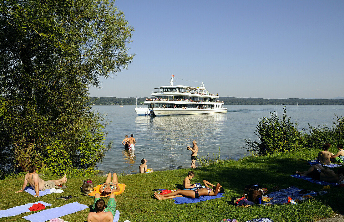 Badegäste am Seeufer, Ausflugsboot im Hintergrund, Bernried, Starnberger See, Bayern, Deutschland