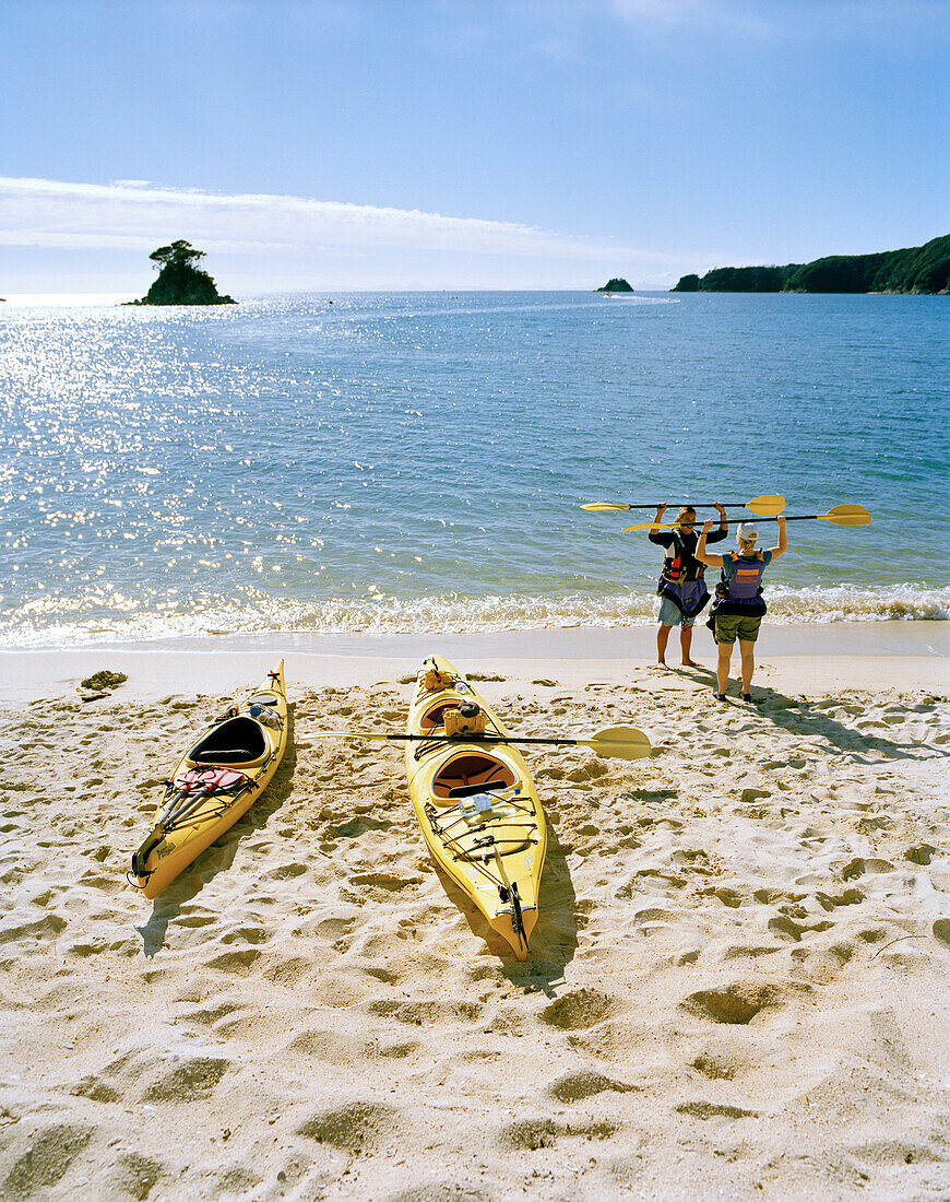 Seakayaking, Menschen mit Paddel stehen am Strand der Torrent Bay, Abel Tasman Nationalpark, Nordküste, Südinsel, Neuseeland