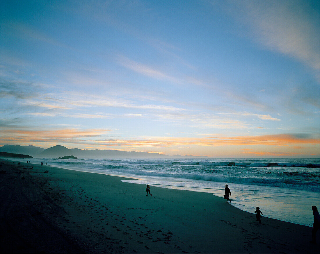 Familie geht abends am Strand entlang, Okuru Beach, Westküste, Südinsel, Neuseeland