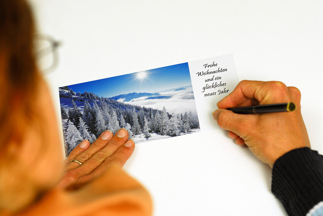 Frau schreibt Weihnachtskarte mit Wintermotiv