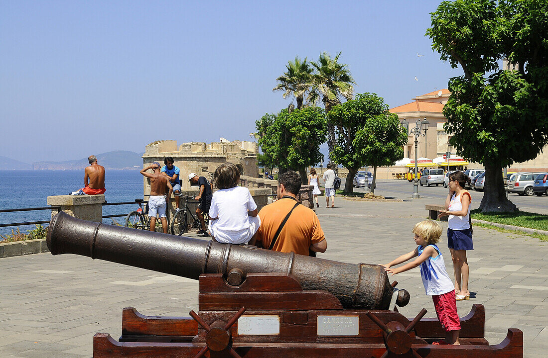 Tourists at an old cannon on the bastion, Alghero, Sardinia, Italy, Europe