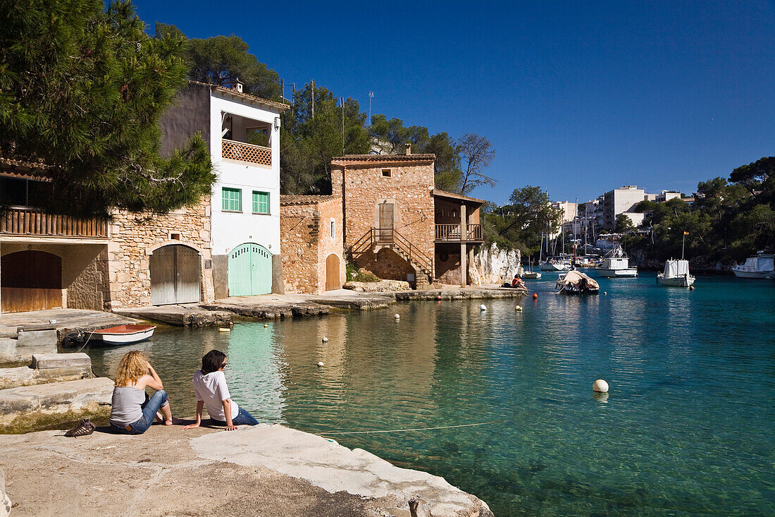 Ein Paar sitzt im Hafen in Cala Figuera im Sonnenlicht, Mallorca, Balearen, Mittelmeer, Spanien, Europa