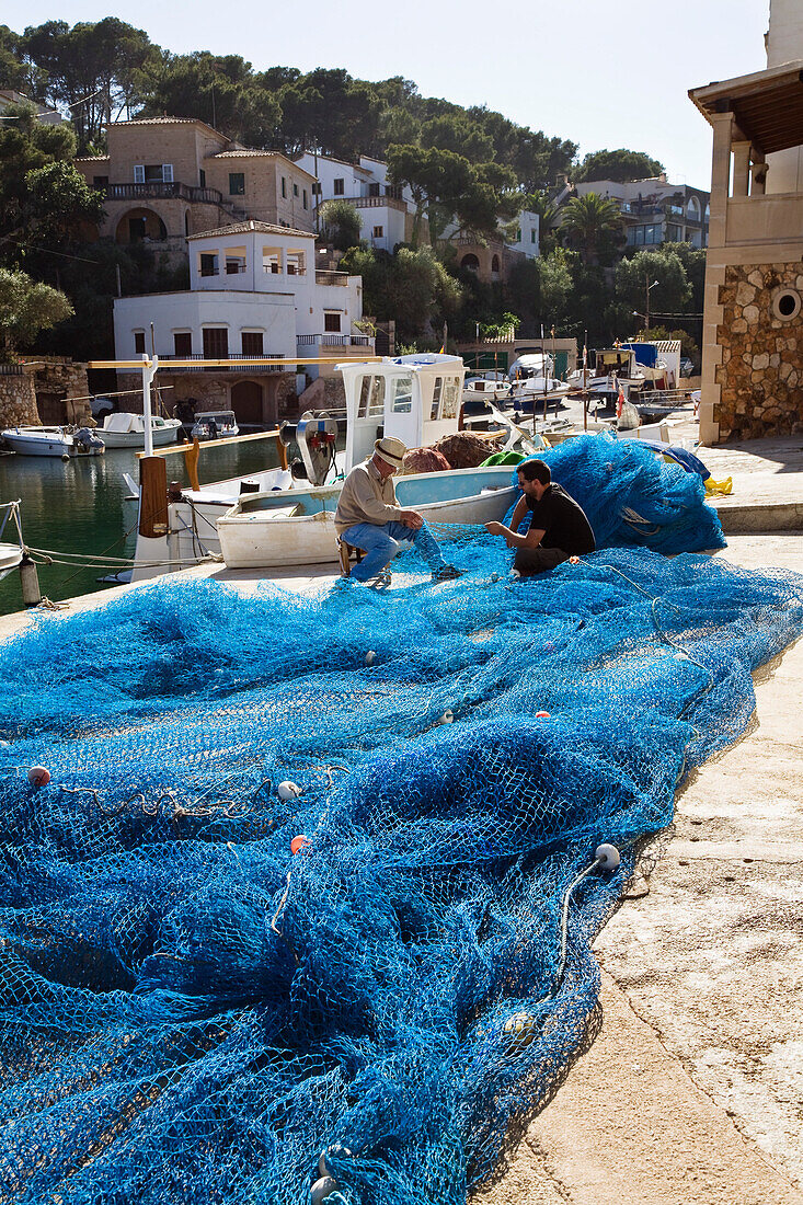 Two fishermen repairing their fishing nets at the harbour of Cala Figuera, Mallorca, Balearic Islands, Mediterranean Sea, Spain, Europe
