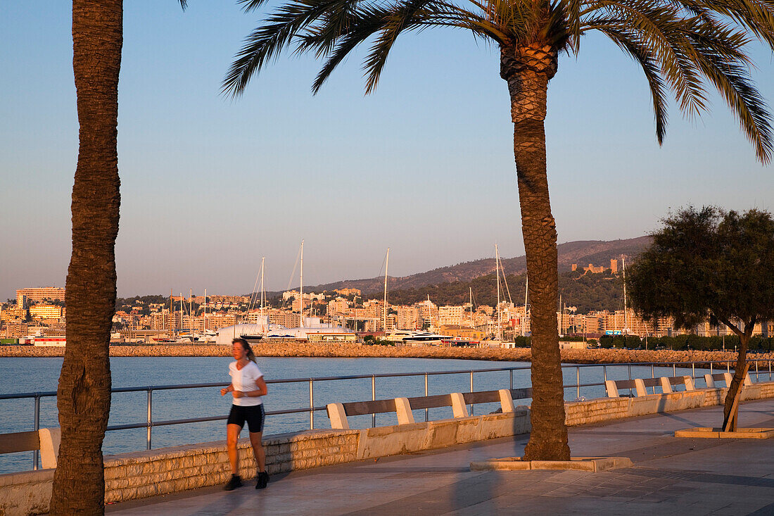 Joggerin auf der Uferpromenade Avinguda Gabriel Roca bei Sonnenaugang, Palma, Mallorca, Balearen, Mittelmeer, Spanien, Europa