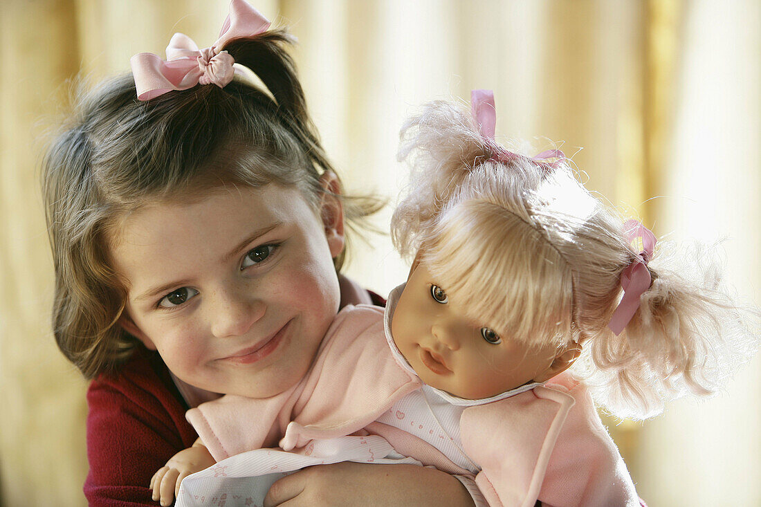 Little girl holding her doll with affection