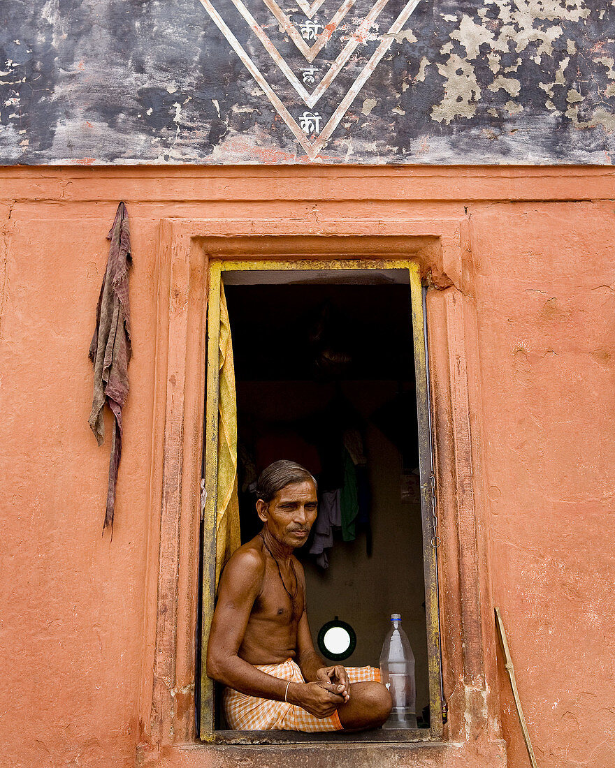 religious man sitting in doorway on the ganges