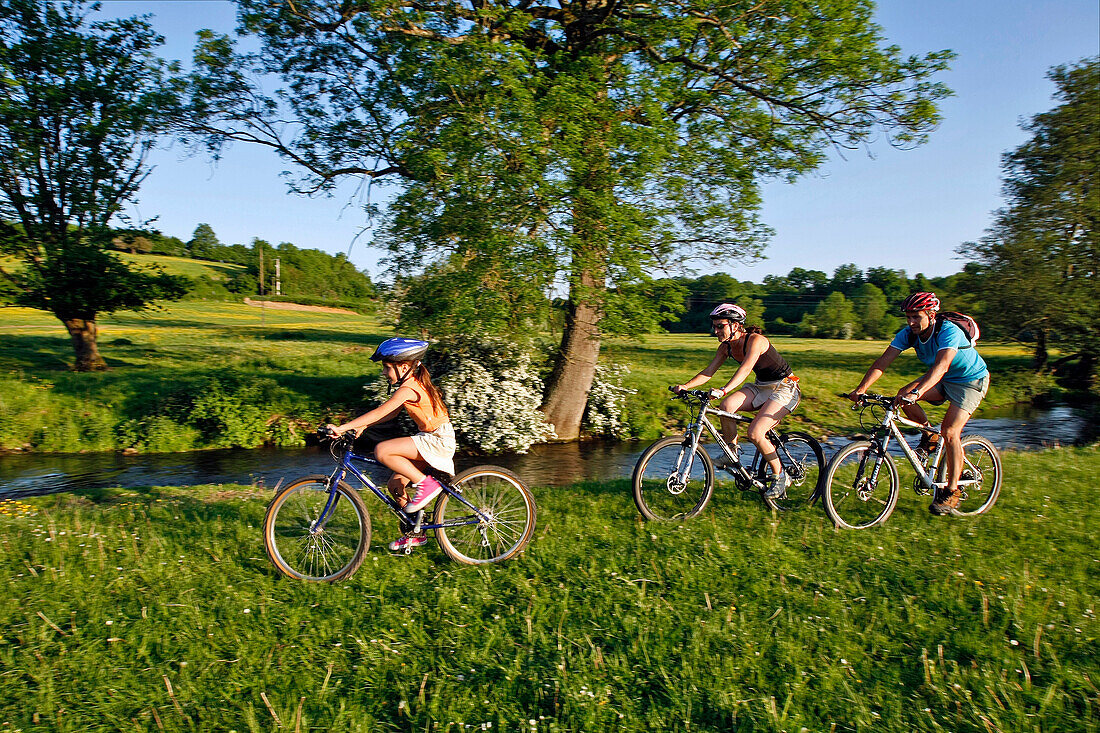 A Couple With Their Family On Mountain Bikes Near A Stream In A Meadow In The Vallee De La Cloche, Ozee, Perche Near Nogent-Le-Rotrou, Eure-Et-Loir (28), France