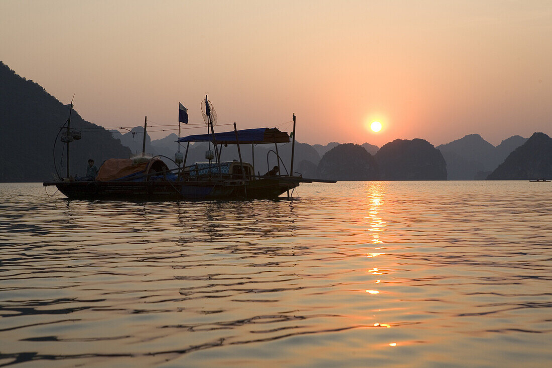 Fischerboot bei Sonnenuntergang in der Halong Bucht im Golf von Tonkin, Vietnam, Asien