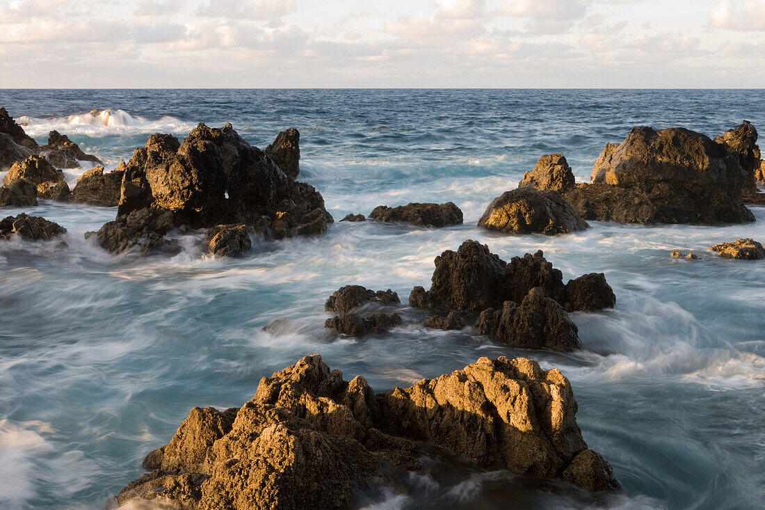 Wellen brechen an Felsen aus Lavastein, Porto Moniz, Madeira, Portugal