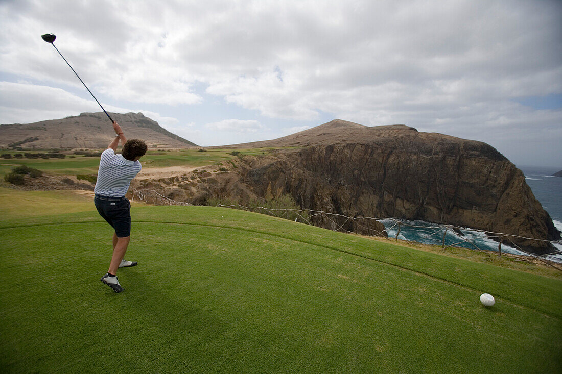 Golfer tees off at hole 14 at Porto Santo Golfe Golf Course, Porto Santo, near Madeira, Portugal