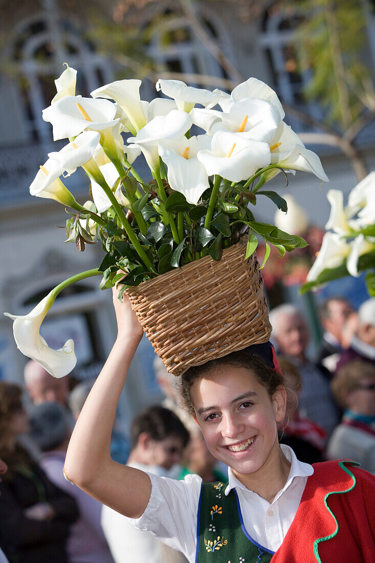 Junge Frau mit Korb voll Calla Blumen bei der Parade zum alljährlich stattfindenden Madeira Blumenfest, Funchal, Madeira, Portugal