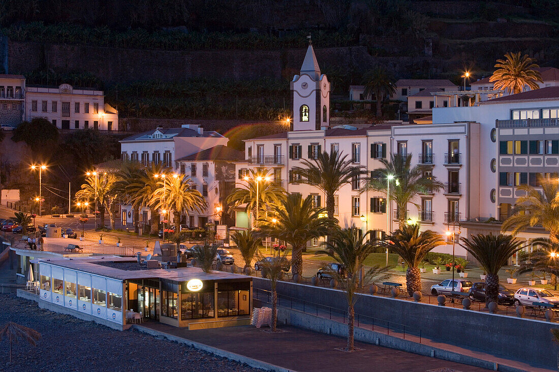 Strandpromenade mit Kirchturm und Enotel Baia do Sol Hotel im Dämmerlicht, Ponta do Sol, Madeira, Portugal