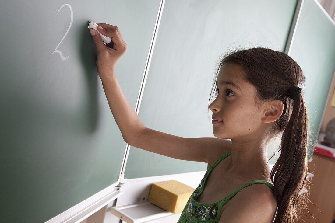 Schoolgirl writing on blackboard, Hambug, Germany