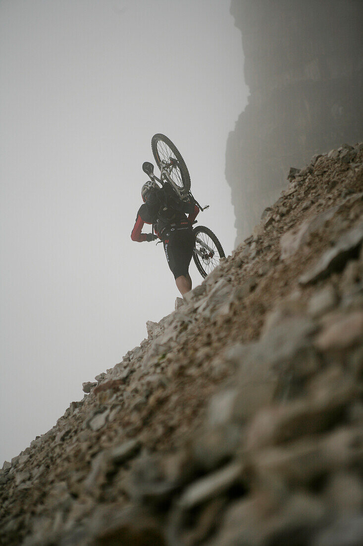 Mountainbiker trägt sein Rad, Drei Zinnen, Dolomiten, Venetien, Italien