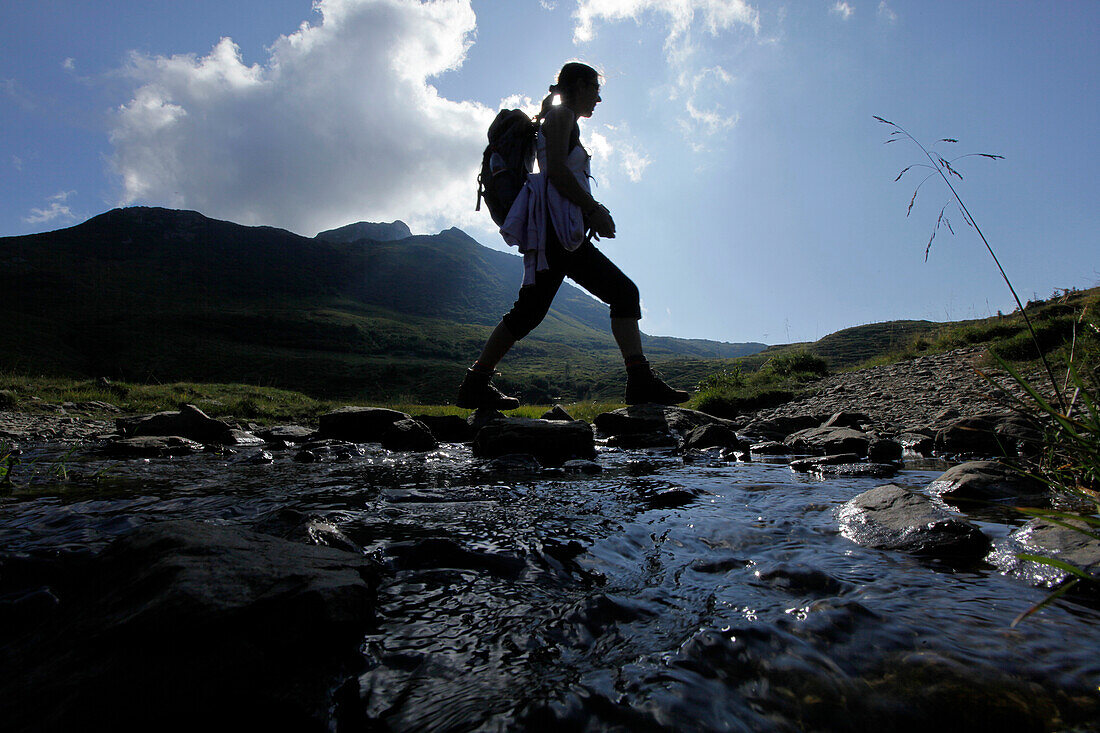 Female hiker passing stream, Carnic Alps, Carinthia, Austria