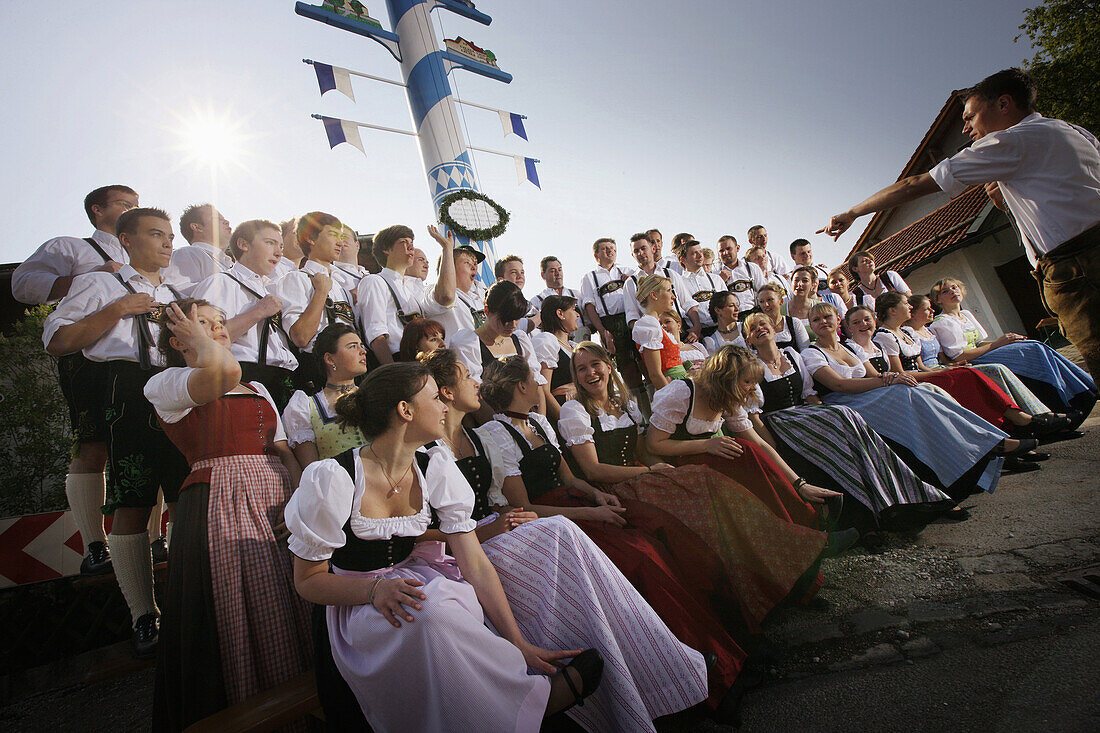 Group of young people wearing traditional costumes in front of may pole, Munsing, Bavaria, Germany