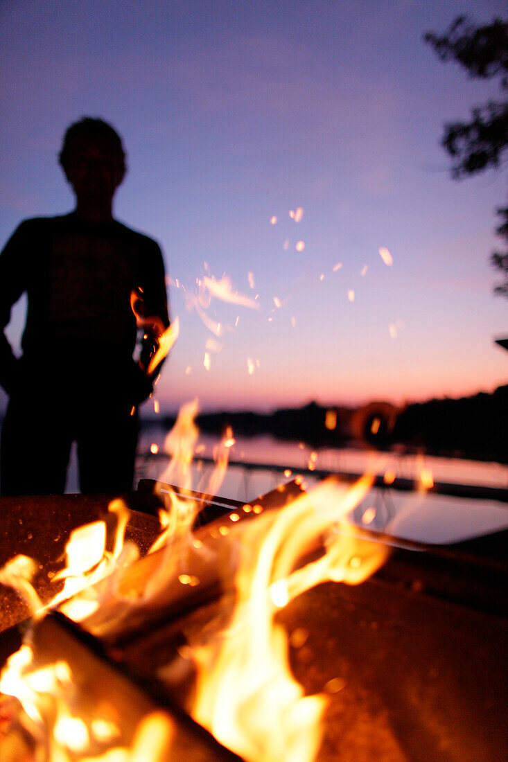 Fireplace, man in background, lake Worthsee, Bavaria, Germany