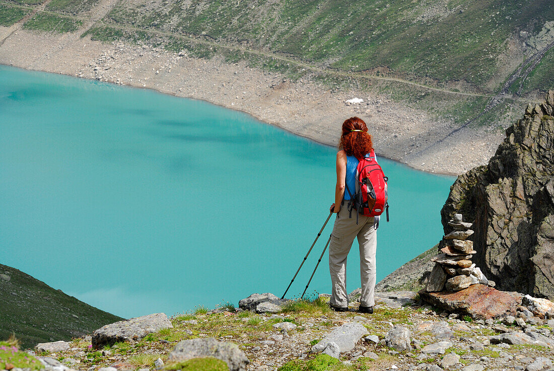 Female hiker looking over Finstertal reservoir, Sellrain, Stubai Alps, Tyrol, Austria