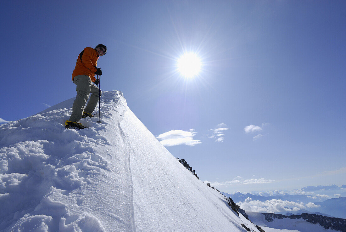 Mountaineer ascending on snow covered ridge towards Hochfeiler, Zillertal Alps, South Tyrol, Italy