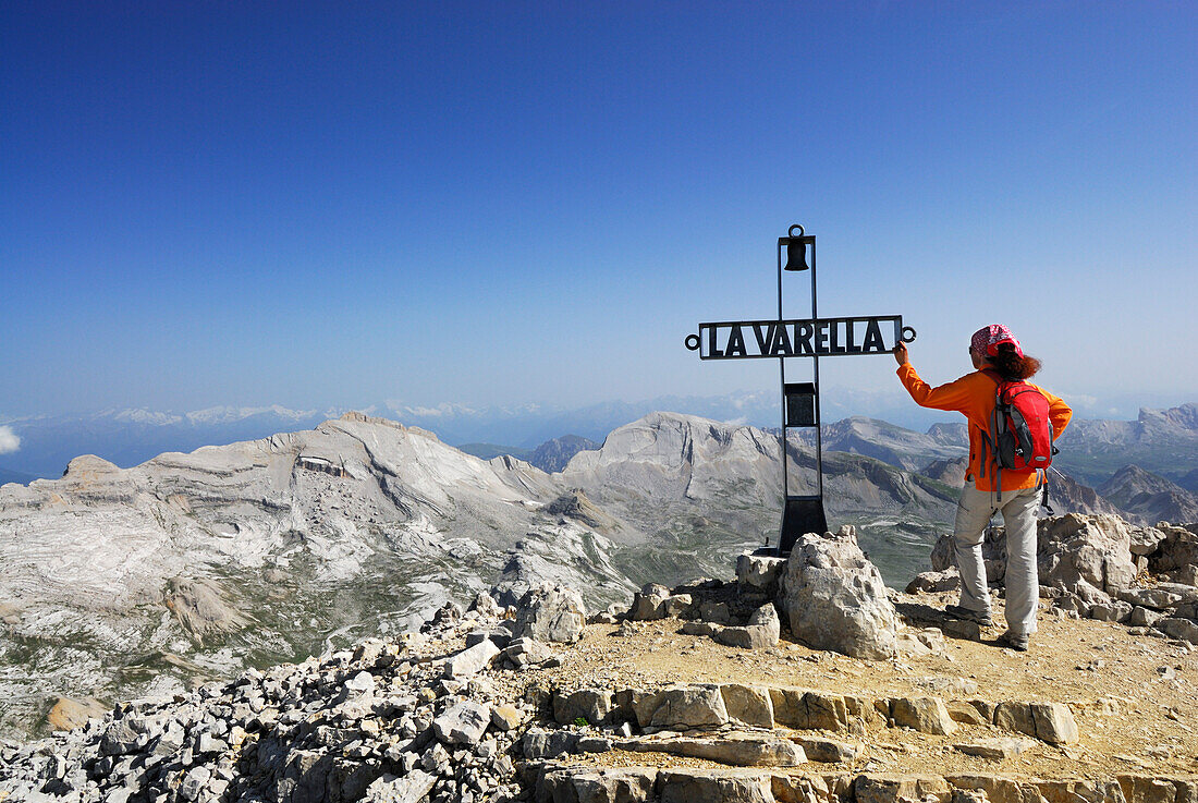 Woman summit cross of La Varella, Zehner and Neuner in background, Naturpark Fanes-Sennes-Prags, Dolomites, Trentino-Alto Adige/South Tyrol, Italy