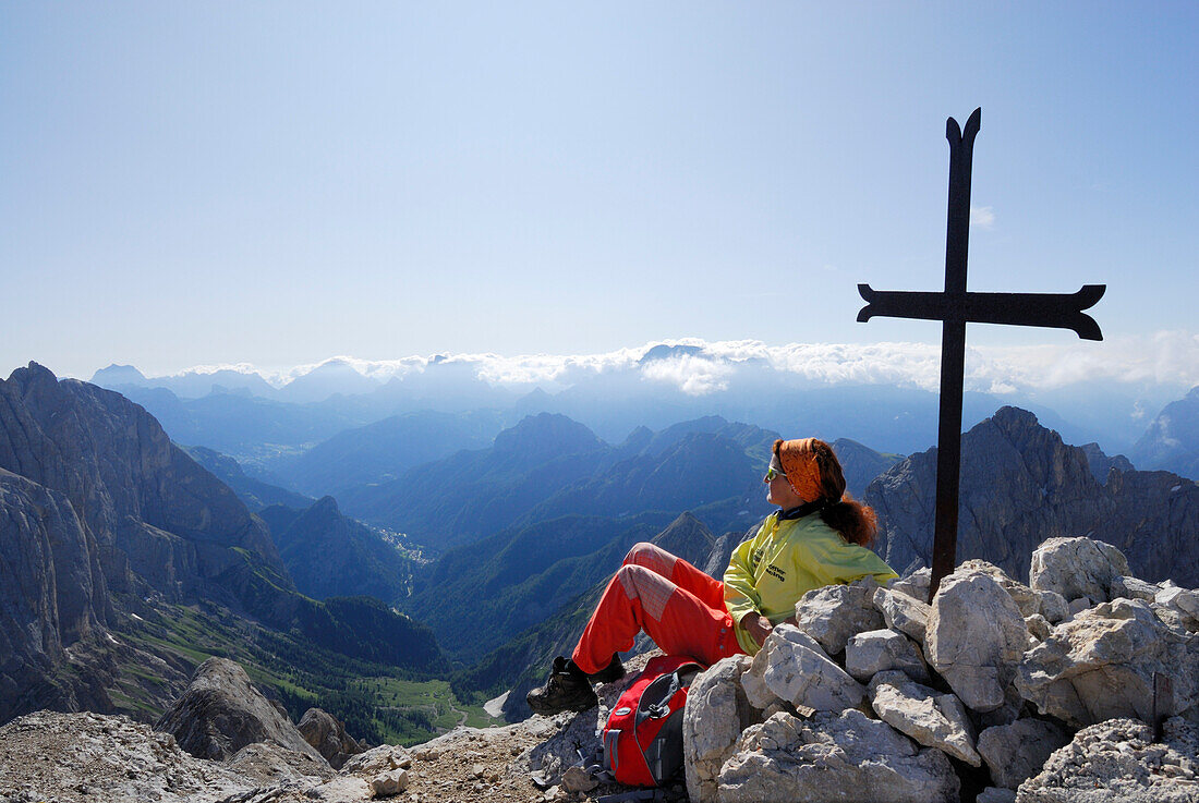 Frau genießt Aussicht am Gipfelkreuz der Cima Ombretta, Marmolata, Dolomiten, Trentino-Südtirol, Italien