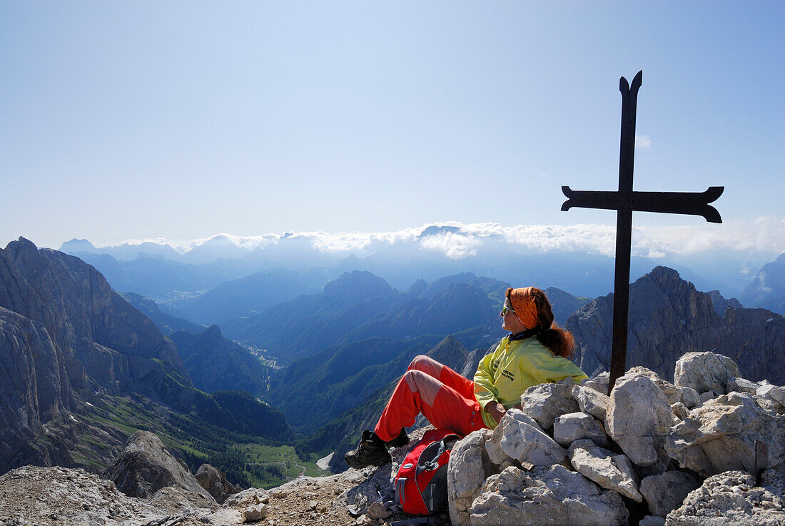 Woman enjoying view at summit cross of Cima Ombretta, Marmolada, Dolomites, Trentino-Alto Adige/South Tyrol, Italy