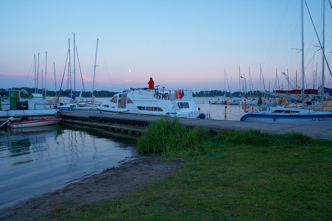 Hausboot mit Crew am Hafen von Ryn (Rhein), Abend, Mond, Jezioro Rynskie (Rheinscher - See), Masurische Seenplatte, Mazurskie Pojezierze, Masuren, Ostpreußen, Polen, Europa