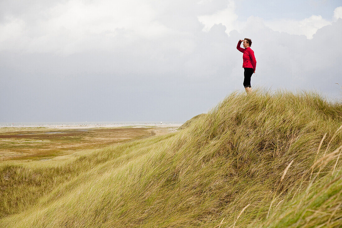 Frau blickt über die Dünen aufs Meer, Insel Amrum, Schleswig-Holstein, Deutschland