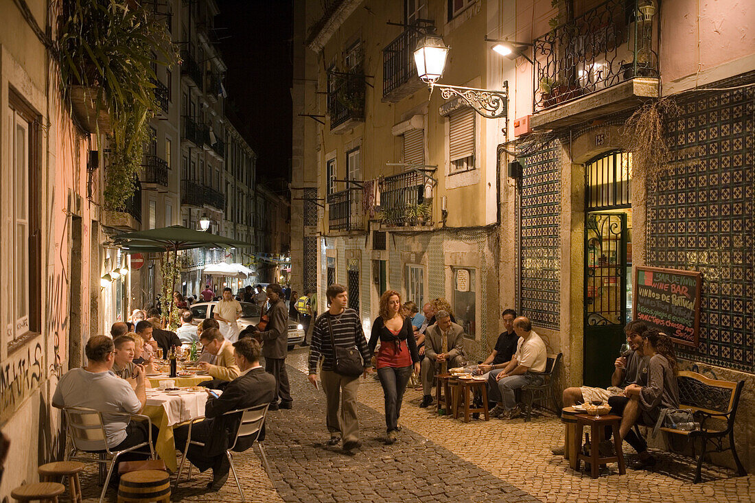 Nachtaufnahme von Menschen vor Alfaia Wein Bar in der Altstadt, Lissabon, Portugal, Europa