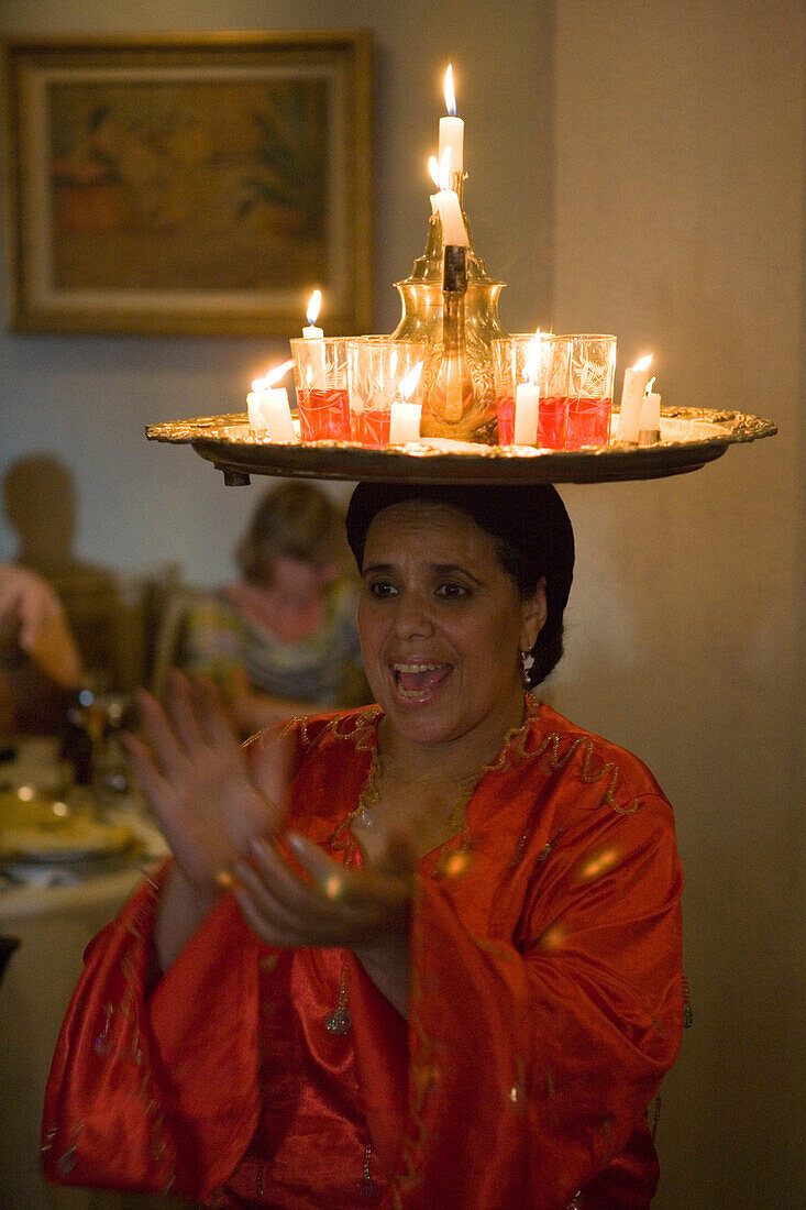 Frau balanciert Tablett mit Gläsern und Kerzen in Restaurant am Jemaa el-Fna Gauklerplatz, Marrakesch, Marokko, Afrika
