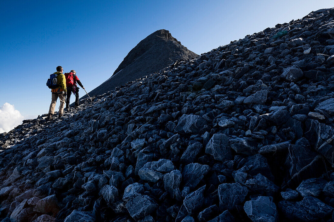 Zwei Bergsteiger wandern über Geröllfeld, Clariden, Kanton Uri, Schweiz