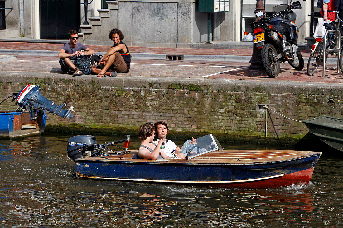 A Pleasure Boat With Two Young People Drinking A Beer On A Canal, Amsterdam, Netherlands, Holland