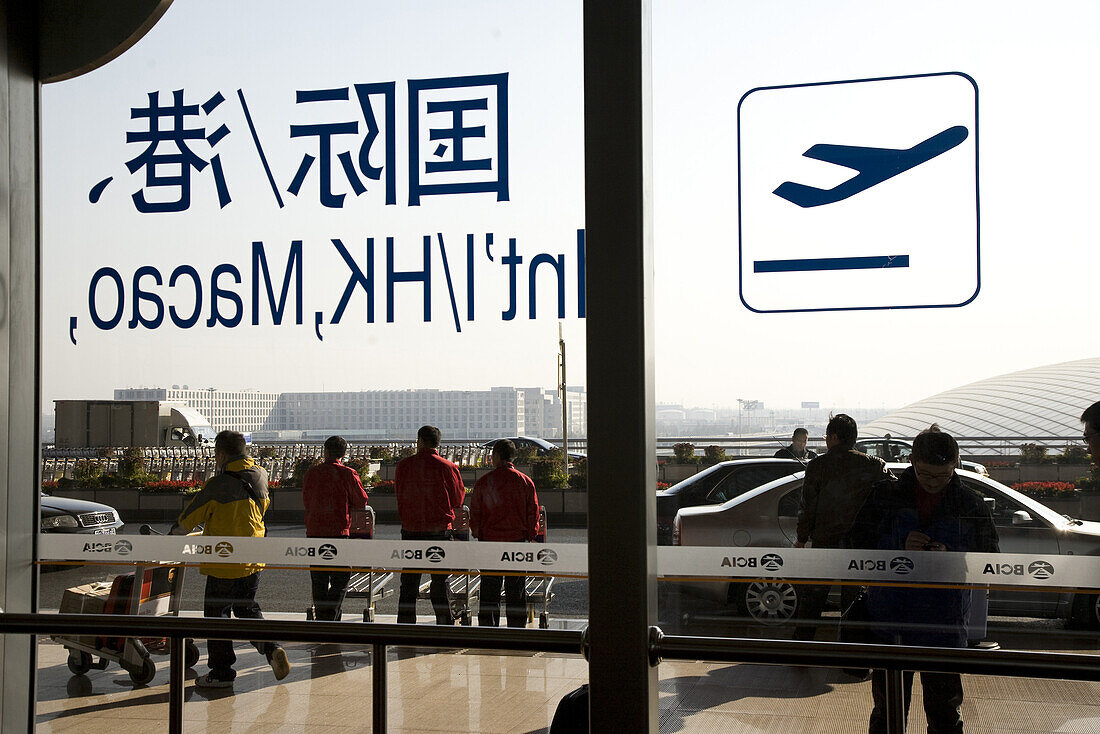 Blick durch Glastür auf Menschen vor dem Internationalen Flughafen Peking, größtes Gebäude der Welt, Beijing, Peking, China, Asien