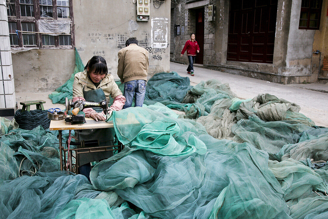 Schneiderin näht Fischernetze auf der Strasse, Jinfeng, Changle, Provinz Fujian, China, Asien