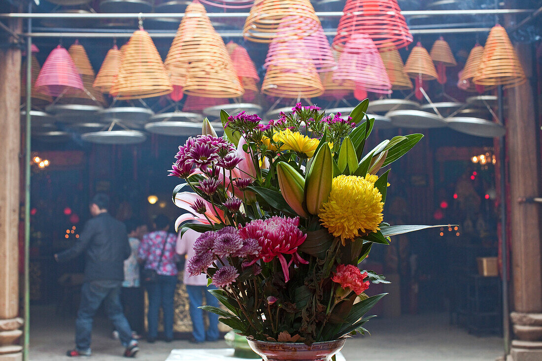 Bunte Blumen und Menschen in einem Tempel in Wanchai, Hongkong, China, Asien