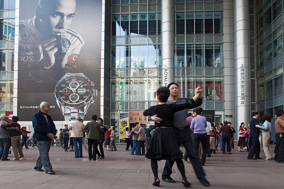 Menschen tanzen unter den Arkaden eines Gebäudes, Nanjing Road, Shanghai, China, Asien
