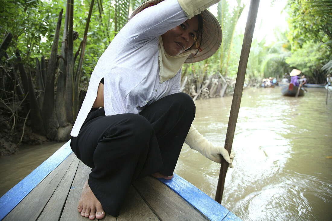 Woman with paddle in a boat on a canal, Mekong Delta, Vietnam, Asia