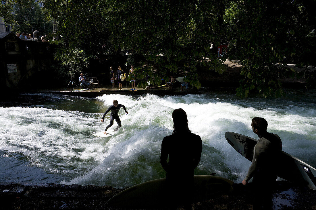 Surfers riding the Eisbach, ice brook waves, English Garden, Munich, Bavaria, Germany, Europe