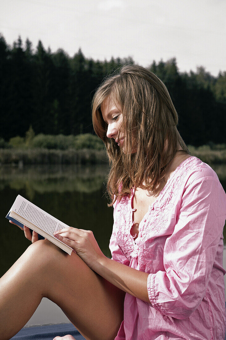 Junge Frau liest ein Buch, Starnberger See, Bayern, Deutschland
