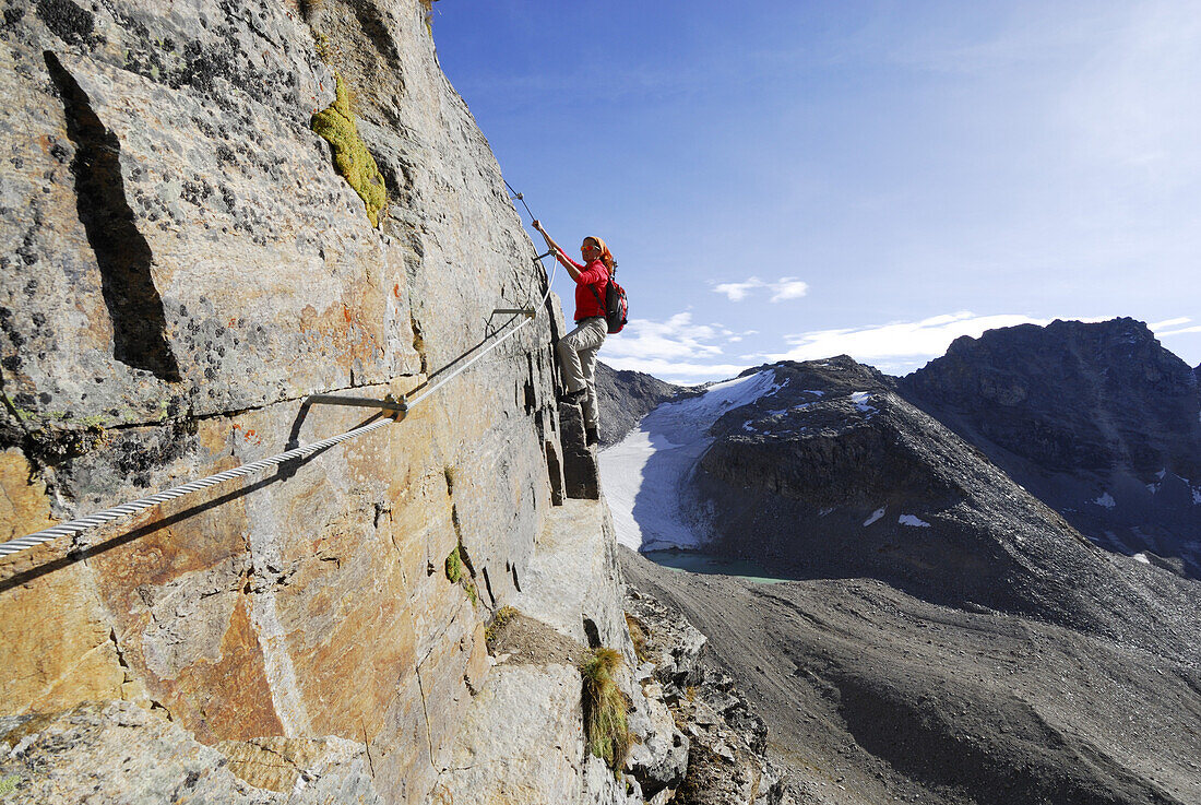 Woman climbing fixed rope route through Tschenglser Hochwand, Ortler range, Trentino-Alto Adige/South Tyrol, Italy