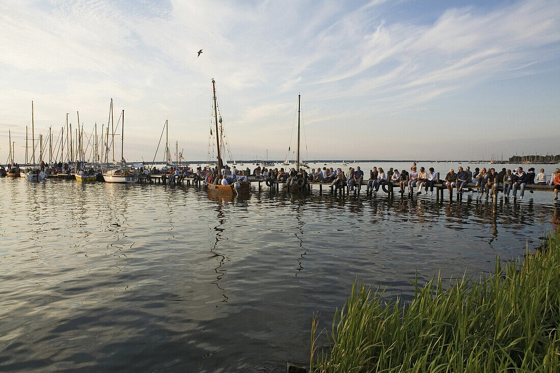 Zuschauer sitzen auf einem Steg am Steinhuder Meer, Niedersachsen, Deutschland