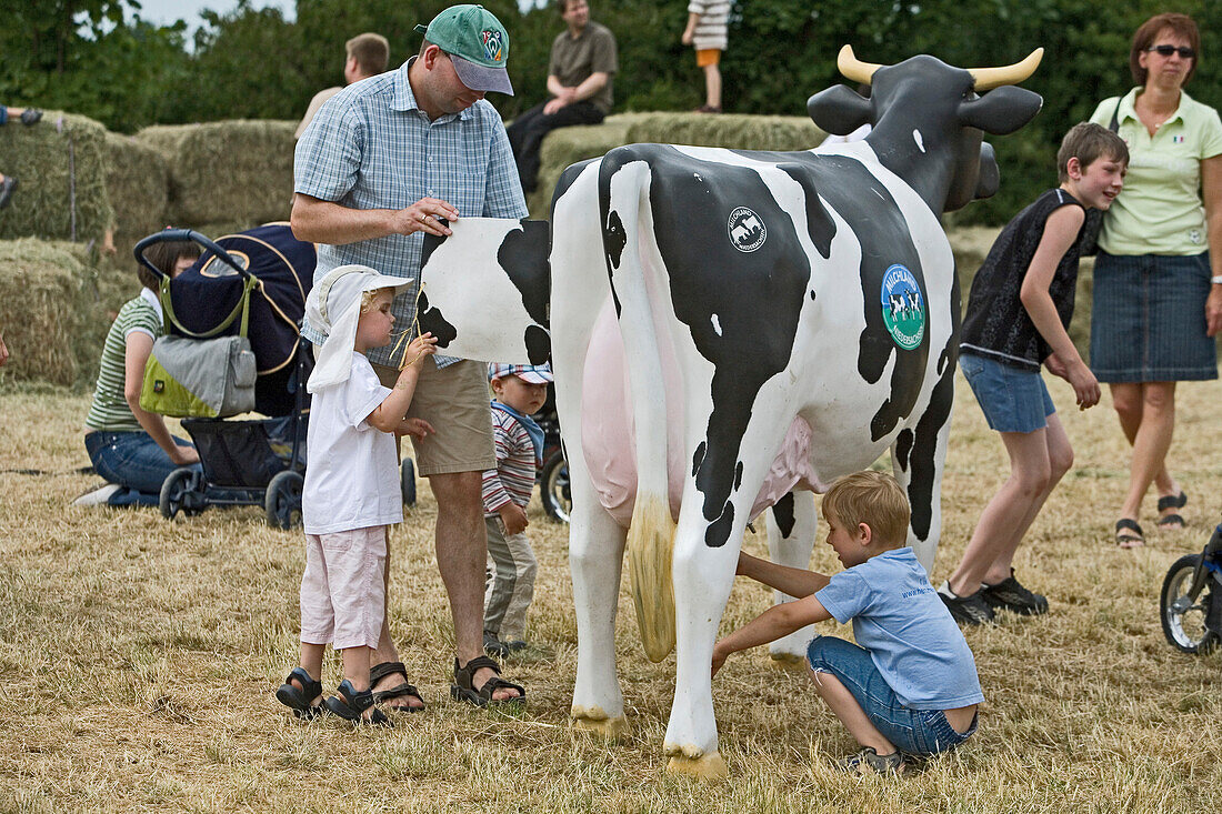 Kinder bestaunen eine künstliche Kuh beim Milchfest auf dem Hemme-Hof in Wedemark-Sprockhof, aufklappares Kuhmodell, Heu, Stroh, Besucher