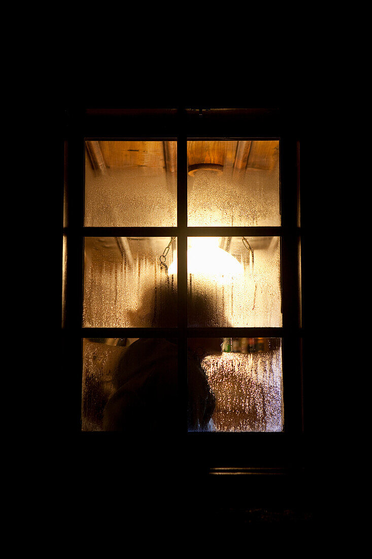 Silhouette einer Frau am Fenster der Albert Heim Hütte, Urner Alpen, Kanton Uri, Schweiz