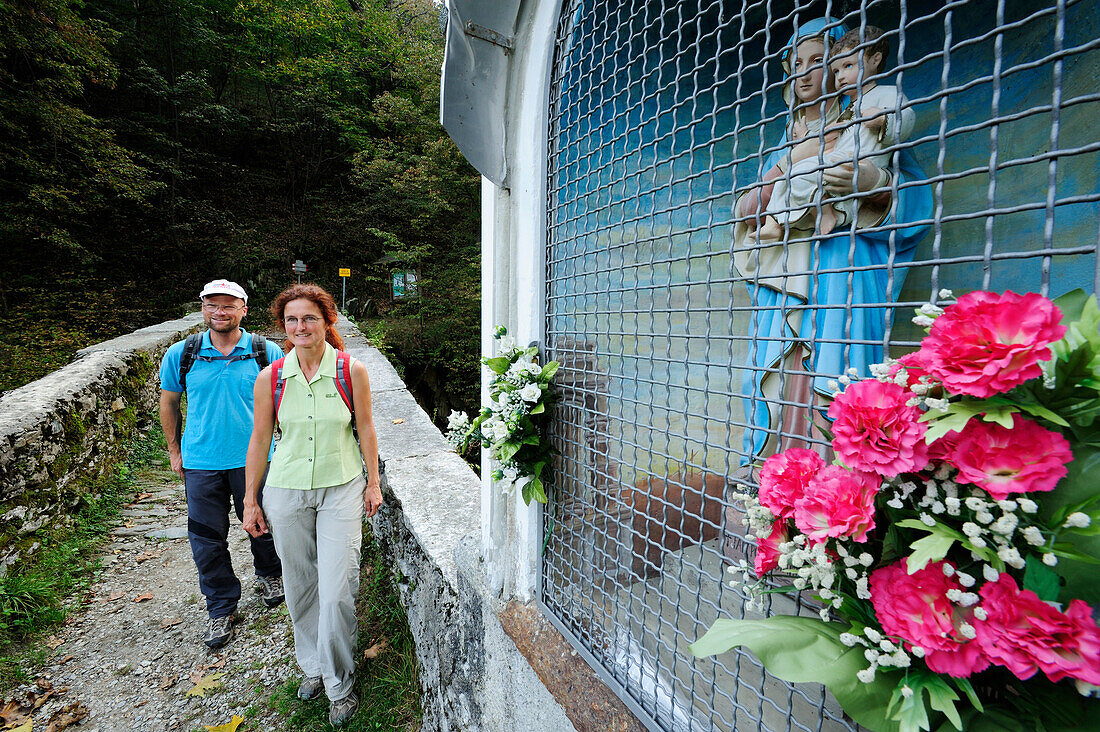 Two hikers passing stone bridge, Via Dei Monti Lariani, Lake Como, Ticino range, Lombardy, Italy