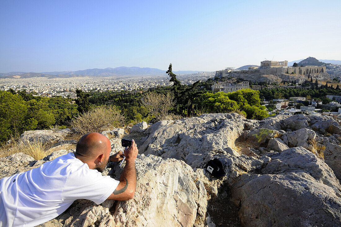 Mann auf dem Filopappos Hügel fotografiert die Akropolis, Athen, Griechenland, Europa