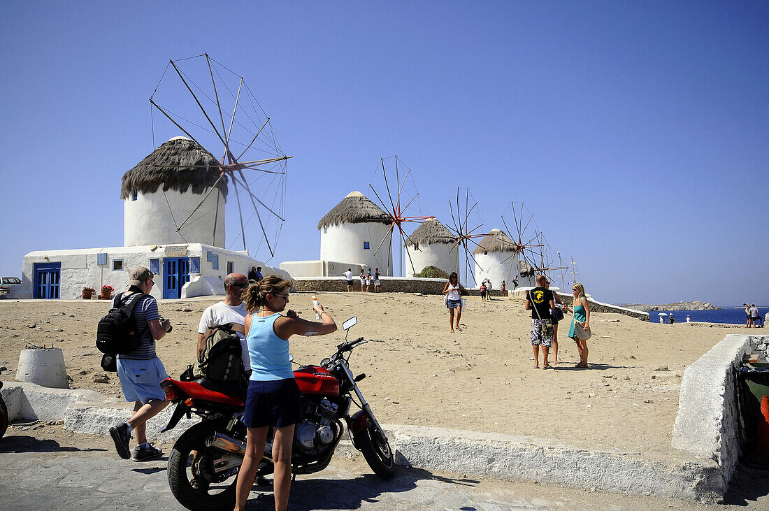 Menschen und Windmühlen im Venetia Viertel unter blauem Himmel, Insel Mykonos, Kykladen, Griechenland, Europa
