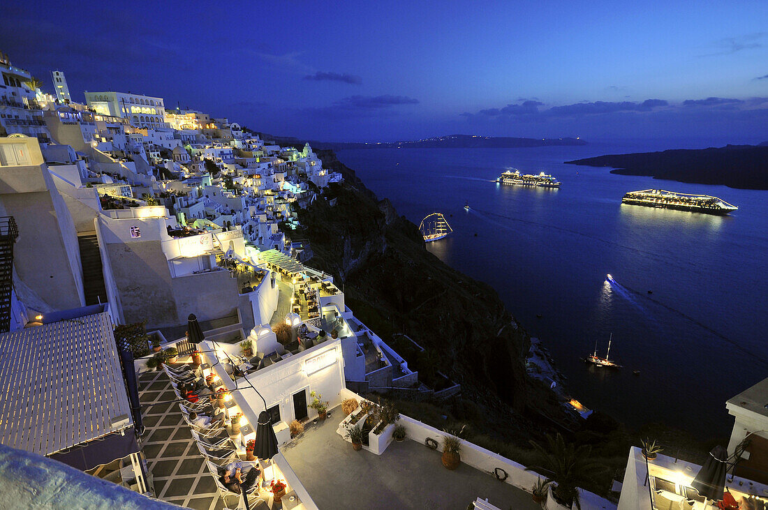 Häuser an der Küste und beleuchtete Fähren am Abend, Fira, Santorin, Kykladen, Griechenland, Europe