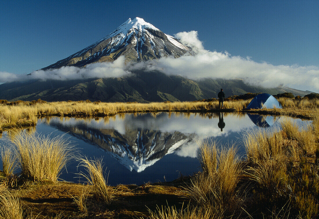 Camping beside tarn reflecting Mt Egmont / Taranaki on the Pouakai Range Egmont National Park New Zealand